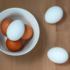 several fresh chicken eggs in a ceramic cup on a wooden background. Healthy eating concept