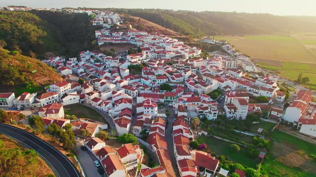 Scenic sunset over a Portuguese village with traditional colourful houses in 4K. Whitewashed traditional windmill in Odeceixe, Aljezur, Portugal, Algarve, near the Nature Park.
