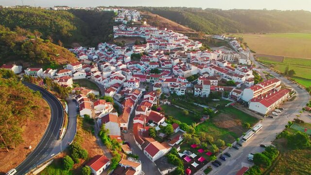 Scenic sunset over a Portuguese village with traditional colourful houses in 4K. Whitewashed traditional windmill in Odeceixe, Aljezur, Portugal, Algarve, near the Nature Park.