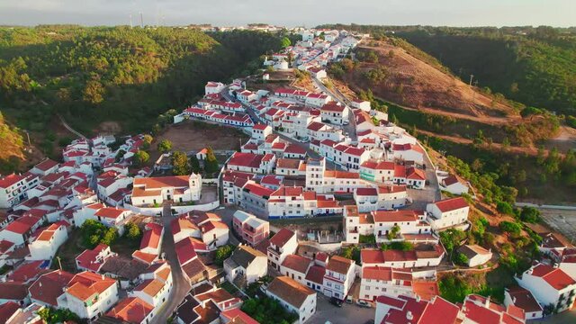 Scenic sunset over a Portuguese village with traditional colourful houses in 4K. Whitewashed traditional windmill in Odeceixe, Aljezur, Portugal, Algarve, near the Nature Park.