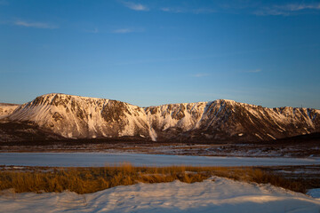 Golden hour light shines on the snow covered mountains