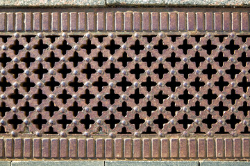 retro drainage grate with cross-hole pattern corroded iron cover of storm system close-up.