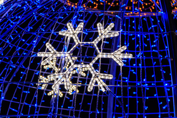 Close-up of glowing led snowflake on Christmas tree at night