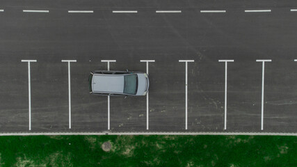 Stupid driver parking. A car parked over multiple parking spots. Car perpendicular to parking spots viewed from above. Aerial drone view of bad parking habit. - obrazy, fototapety, plakaty