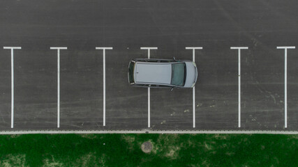 Stupid driver parking. A car parked over multiple parking spots. Car perpendicular to parking spots viewed from above. Aerial drone view of bad parking habit.