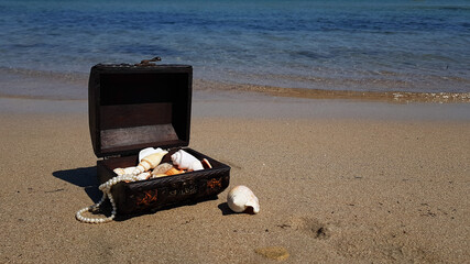 a treasure chest on a sandy beach.treasure with seashells and jewels found in the sea