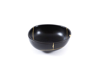 Isolated Japanese kintsugi black bowl restored with real gold , black pottery with gold cracks