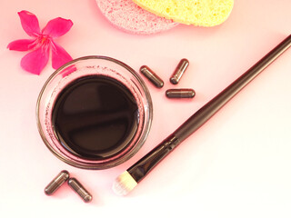 Close up of the charcoal mask in the glass bowl and cosmetics tools to apply the face mask. Flat lay