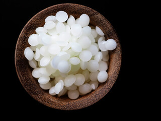 White refined cosmetic beeswax pearls on black background - obrazy, fototapety, plakaty