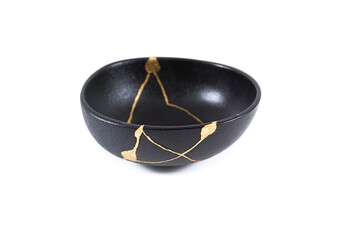 Isolated Japanese kintsugi black bowl restored with real gold , black pottery with gold cracks