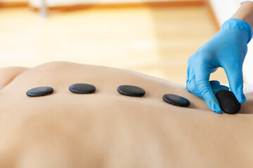 Closeup on young woman receiving hot stone massage