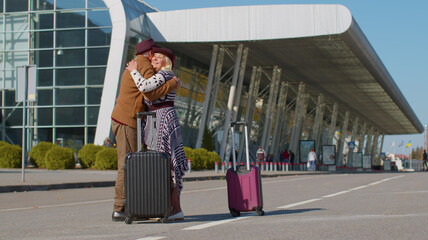 Elderly old grandmother grandfather retirees tourists reunion in airport terminal after long separation traveling. Lovely senior couple husband and wife happily hugging meeting after business trip