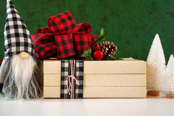 Christmas holiday on-trend Farmhouse aesthetic stack of books close up styled with red and black plaid ribbon bow, white tree ornaments and gnome.