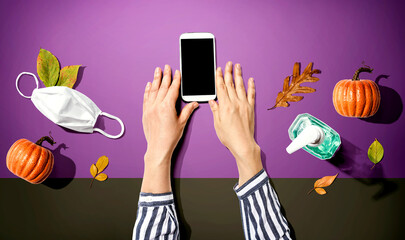 Smartphone with a mask and a sanitizer bottle in Autumn