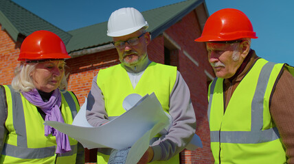 Architect with senior civil engineers discussing project work with blueprint of building house....