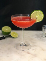 Red strawberry daiquiri  in a coupe glass on a marble bar
