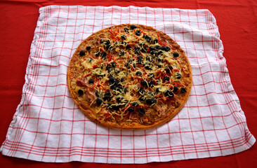 a delicious large home-made Italian pizza on a white kitchen towel	