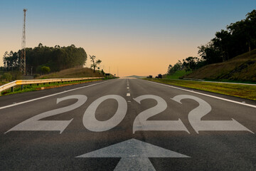 Empty asphalt road and New Year 2022 concept. Driving on an empty road to 2022 goals with the sunset.