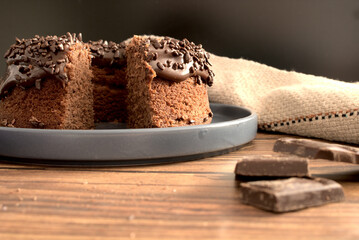 Homemade chocolat cake on wooden background, with pieces of chocolate on the side