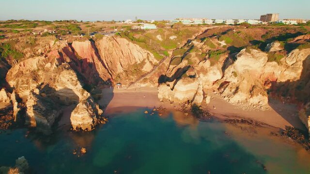 Aerial view of Praia do Camilo by rocky coastline in Lagos, Algarve, Portugal. Scenic view of Praia do Camilo from above - a tourist crowded and famous relaxing holiday beach in 4K.
