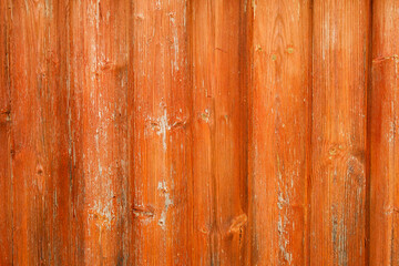 Textured wooden surface painted with orange paint, exfoliated under the influence of time and the environment.