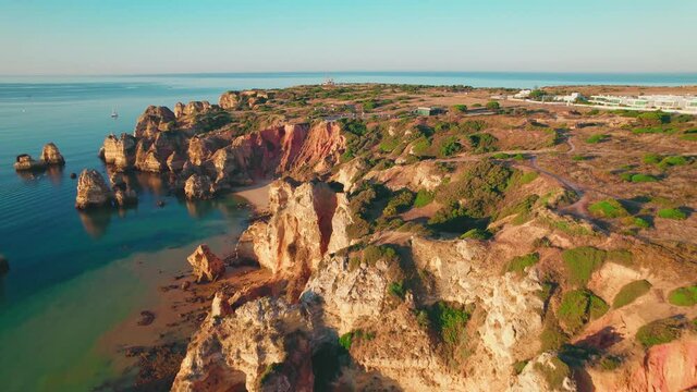 Aerial view of Praia do Camilo by rocky coastline in Lagos, Algarve, Portugal. Scenic view of Praia do Camilo from above - a tourist crowded and famous relaxing holiday beach in 4K.