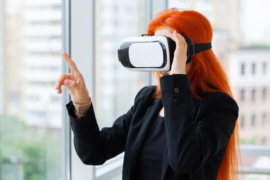 Pretty beautiful cute excited woman in VR headset trying to touch objects in virtual reality