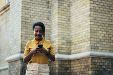 African american woman using a smartphone while walking in the city street