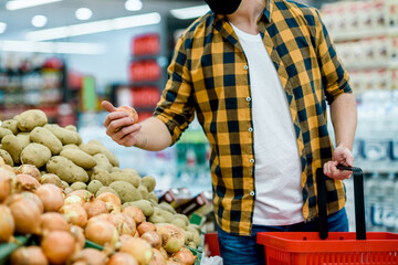 Young handsome man in a supermarket wearing protective mask while grocery shopping