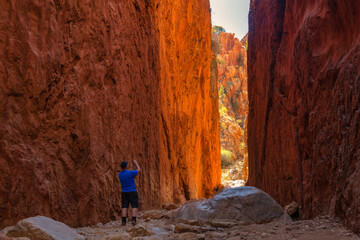 An adventurous male taking a picture of the Standley Chasm rocky cliffs in Australia
