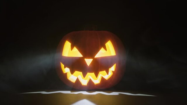 Halloween pumpkin with smoke around it. Glowing pumpkin on dark background. Close-up in 4K, UHD