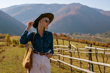 Outdoor fashion portrait of confident blonde woman wearing stylish sunglasses, hat, blue denim...