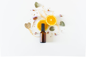 Beauty spa beige composition with amber bottle, orange slices and eucalyptus and flowers dried leaves on white background. Flat lay, top view. Female beauty treatment routine concept.