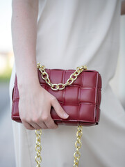 A woman's hand holds a red bag. Close-up. A woman on a walk. Business style, style element, accessory.