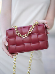 A woman's hand holds a red bag. Close-up. A woman on a walk. Business style, style element, accessory.