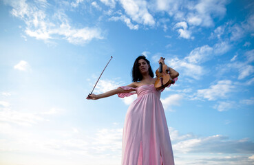Beautiful young woman playing violin. Violinist woman playing violin live.