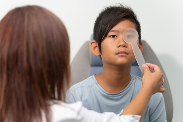Asian boy in a consultation of an ophthalmologist woman