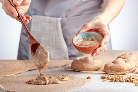 closeup isolated image of a caucasian woman preparing sweet Turkish pastry rolls with tahini and petimezi (tahin pekmez) She mixes the ingredients and spreads it on the flat dough using wooden spoon