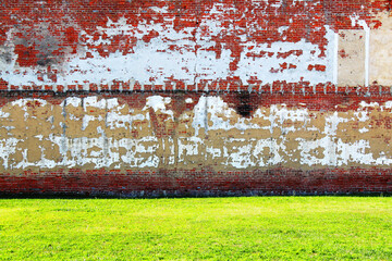 large old abandoned red brick and stucco peeling decaying factory warehouse building and green grass lawn