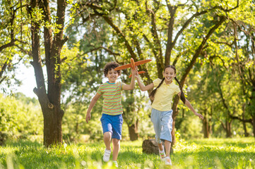 Boy and girl running with toy airplane