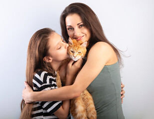 Happy young mother hugging her red maine coon kitten and daughter. Closeup portrait