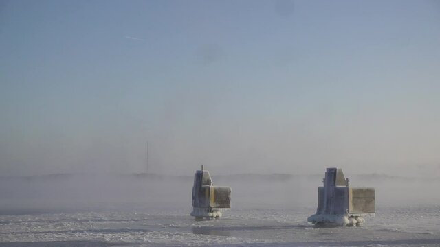 Ice covered mooring pollard or docking pillar by the Baltic sea in Helsinki, Finland with sea smoke moving in slow motion around them.