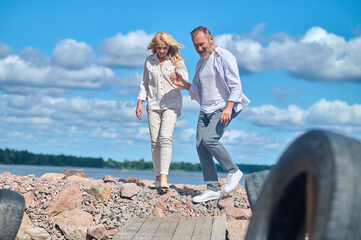Man and woman walking on stones near sea