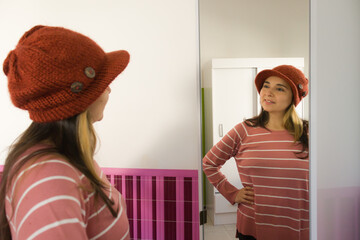 joven mujer morena feliz frente al espejo probándose o eligiendo ropa de abrigo con enfoque...