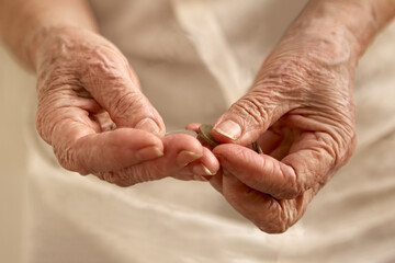 Fototapeta na wymiar Old woman's wrinkled hands counting small coins