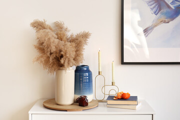 Aroma candles with vases and books on table in room