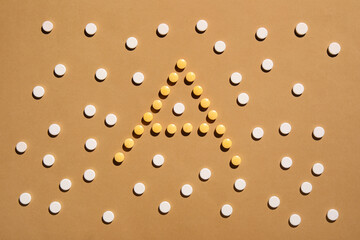 Letter A made of pills on color background