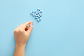 Female hand with pills on blue background