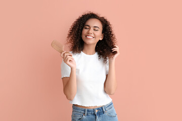 Young African-American woman with comb on pink background