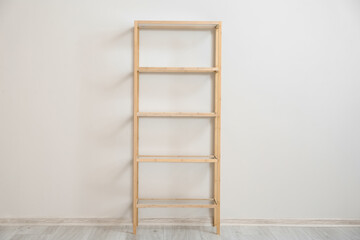 Stylish wooden shelf unit near light wall